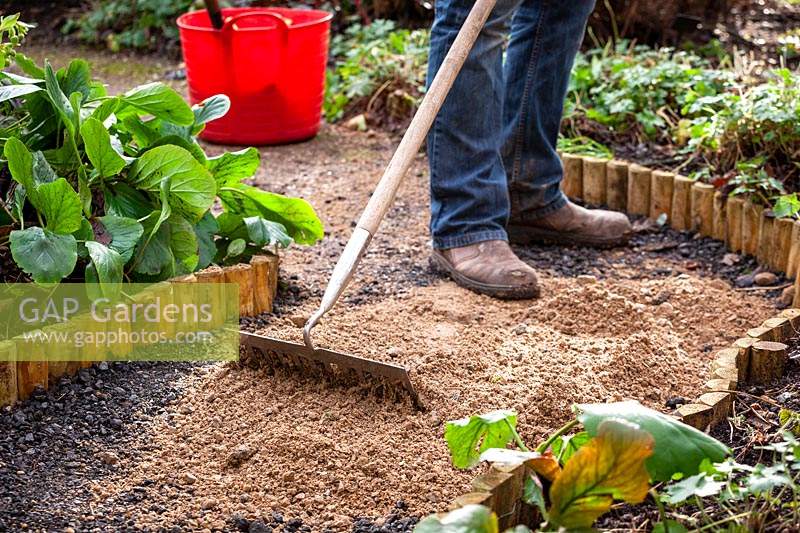 Resurfacing a path by spreading gravel, raking it even and tamping it down