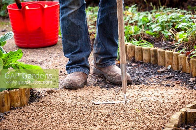 Resurfacing a path by spreading gravel, raking it even and tamping it down