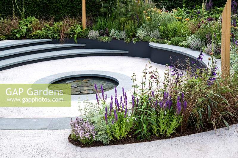 Spiralling pathway leading to sunken seating area with planting including Penstemon, Salvia, Digitalis and Roses - The Cancer Research UK Garden. Pledge Pathway To Progress - RHS Hampton Court  Palace Garden Festival 2019 