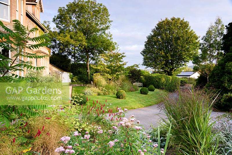 Front garden viewed from mound planted with herbaceous perennials, grasses and shrubs at the Old Vicarage, Weare, Somerset, UK.