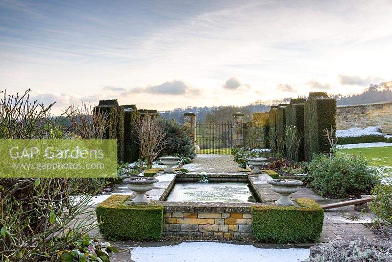 A rectangular pond with Buxus - Box - 'corners', set in formal garden