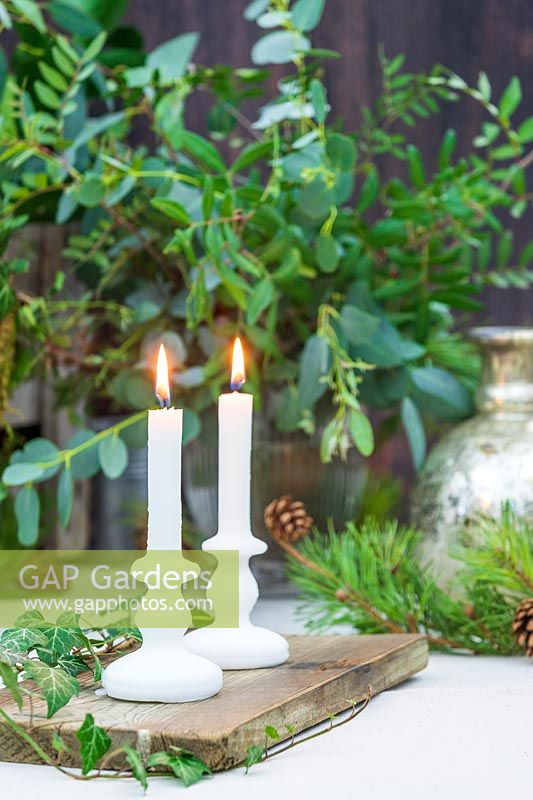 White candles on wooden board as table decoration