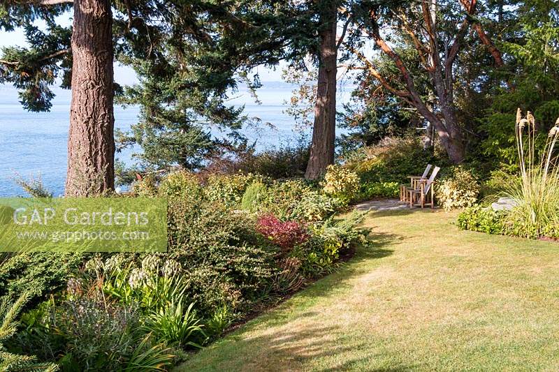 View down lawn towards Puget Sound. Small sitting area placed to take advantage of view. Borders planted wit collection of deer-resistant, drought tolerant plants
