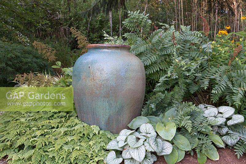 A rustic blue-green urn framed by shade-loving perennials 