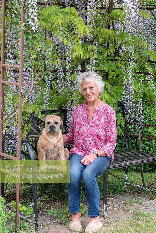 Josephine Hoy sits on a wisteria arbour with Monty, her border terrier, in her four acre garden.
