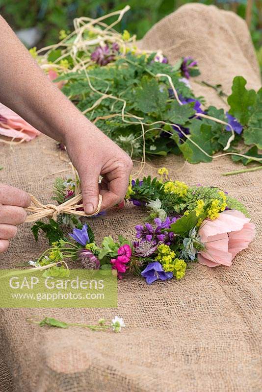 Step-by-step Making a Floral Head Dress. Step 12:  a raffia bow is tied on the completed wire of cut flowers.