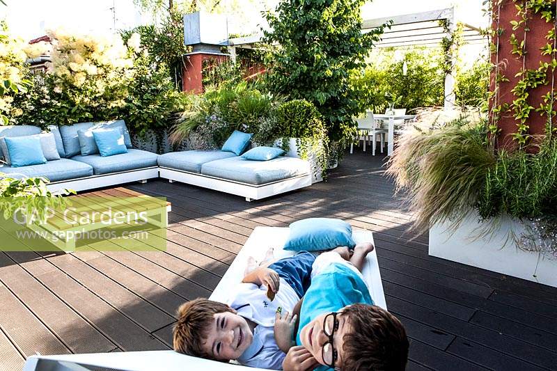 Decked terrace with seating area and children on a lounger looking at camera