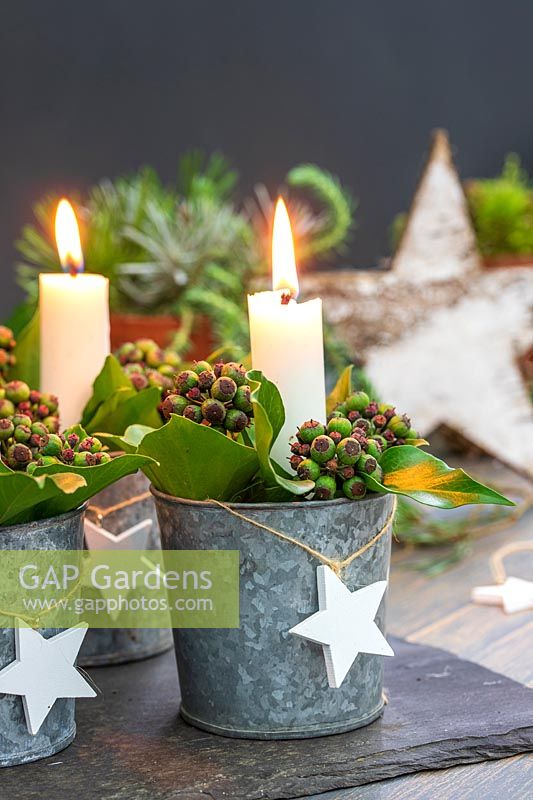 Table decoration featuring candles in miniature galvanised buckets filled with Ivy berries and Bay leaves