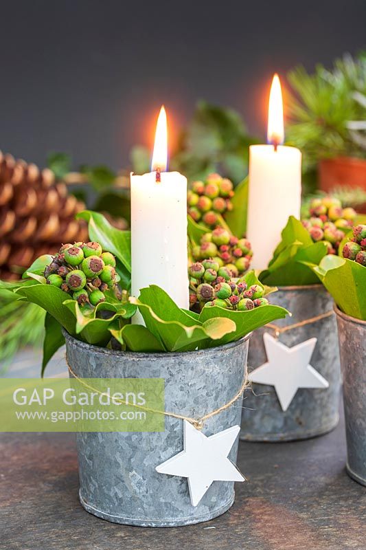 Table decoration featuring candles in miniature galvanised buckets filed with Ivy berries and Bay leaves