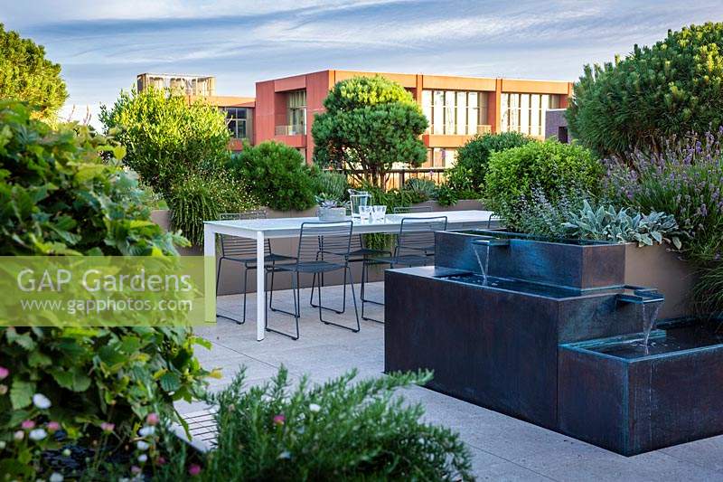 Bronze water feature on London roof terrace with view to surrounding buildings and container grown plants