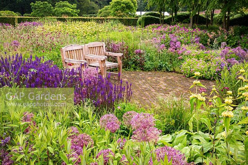 Wooden seats in The Perennial Meadow, at Scampston Hall Walled Garden, North Yorkshire, UK. 