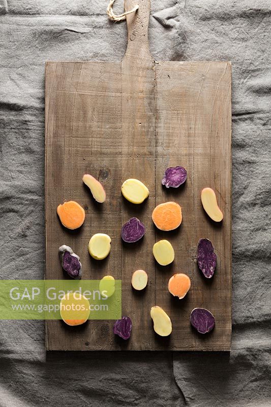Different potato varieties displayed in wooden chopping board. 