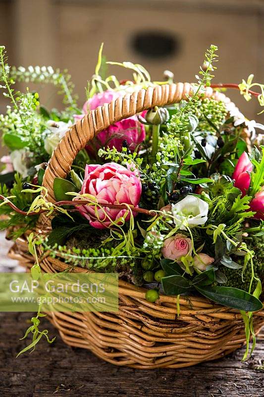 Floral arrangement in basket with roses, capsella busta pastoris, Hypericum and Eustoma.