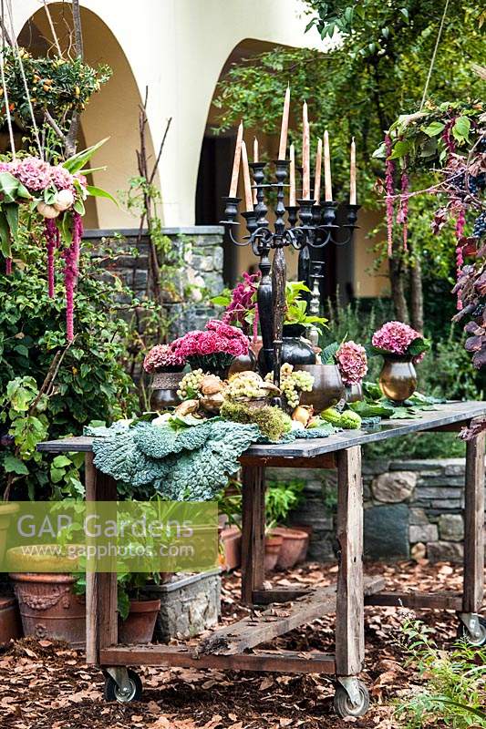 Autumn table decorated with hydrangeas, carnations, amaranth, pumpkins, grapes, savoy cabbage and mushrooms and candlesticks