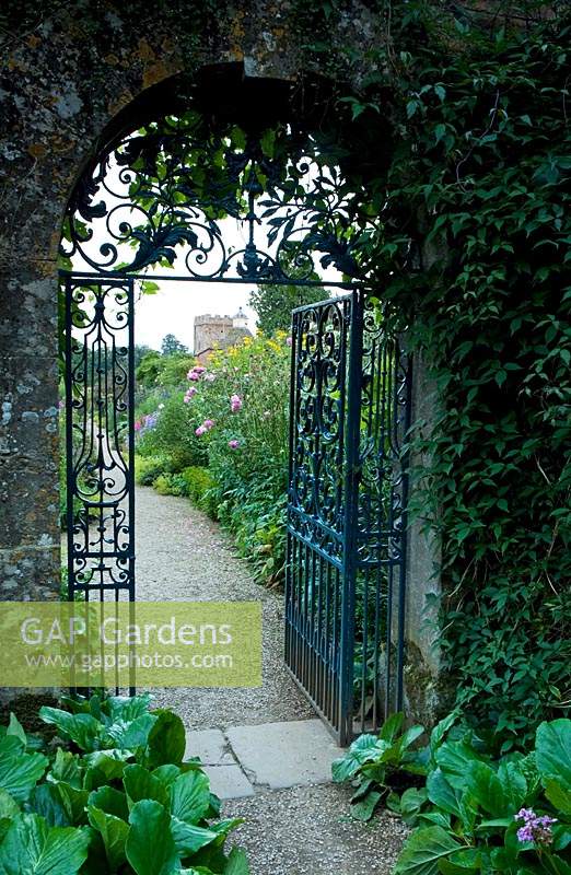 Ornate metal gate through to a separate area of the garden, arch in dividing wall