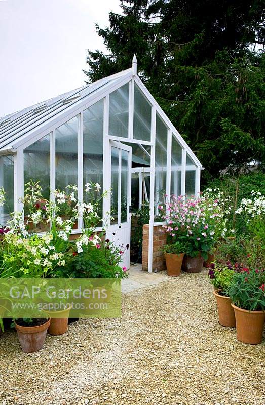Classic greenhouse with container display at entrance on gravel