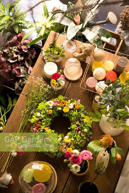 Looking down on table in a florist shop, a flower crown with candles and cut foliage and flowers