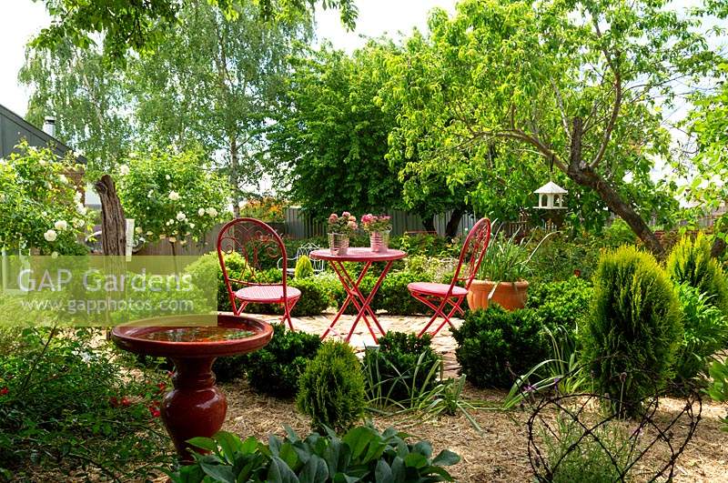 View to red table and chairs in centre of garden.  