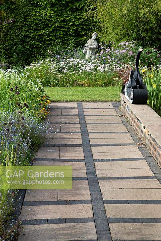 Geometric paving leading to the wildflower bed with sculpture 