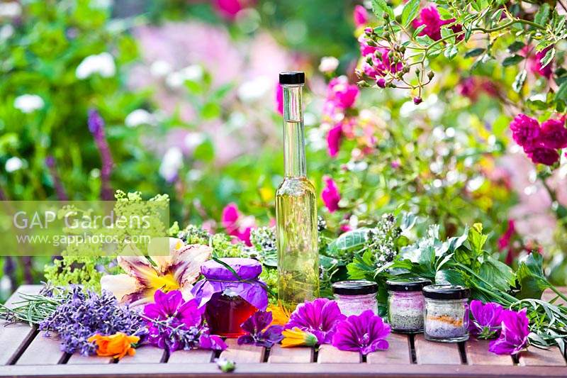 Herb and edible flower products on table with picked flowers heads
