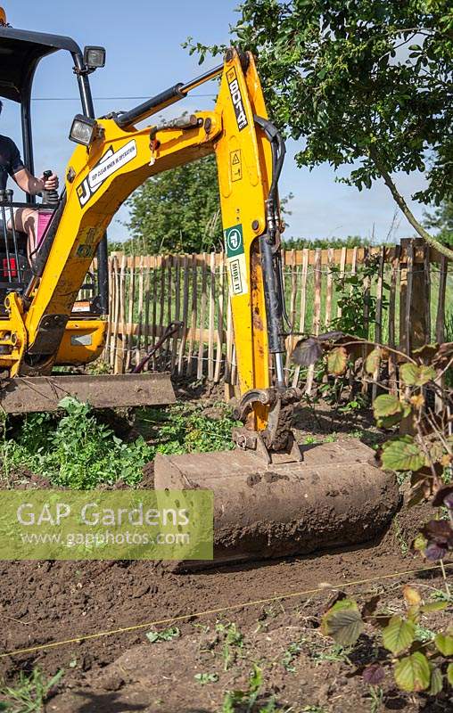 Small digger being used to scrape away top soil