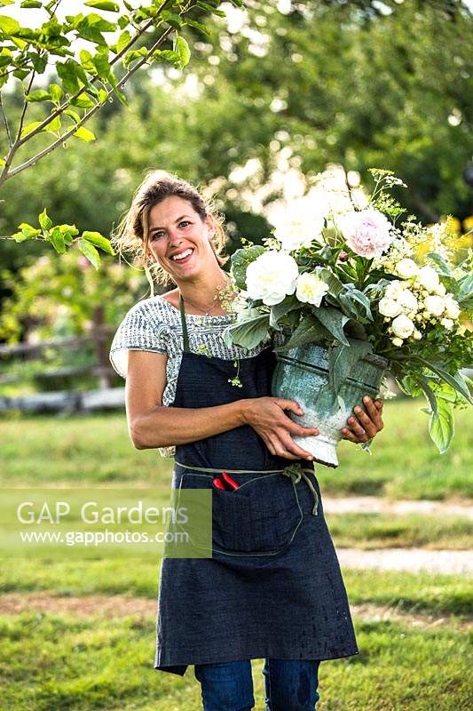 Woman wearing work apron after picking a bucketful of cut flowers from the fields