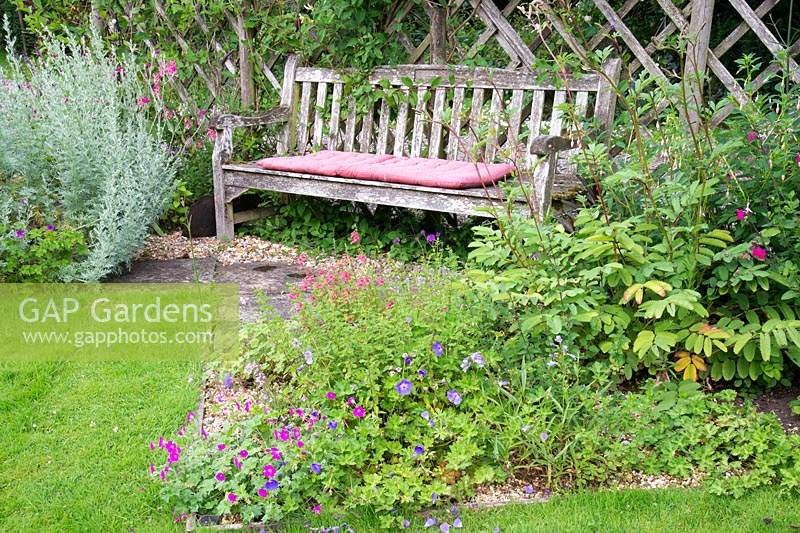A wooden bench with flowerbeds on either side