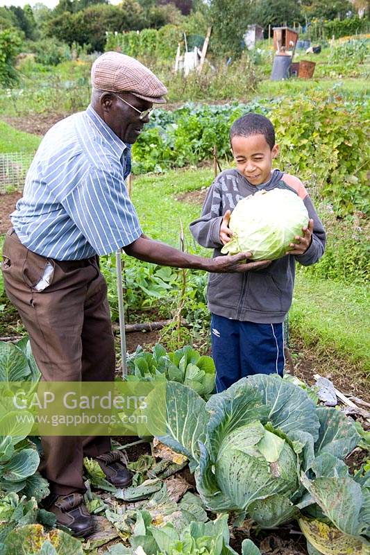 Man giving his grandson a huge Cabbage to hold