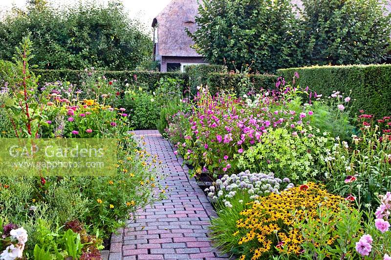 Paved path going through mixed summer borders. 