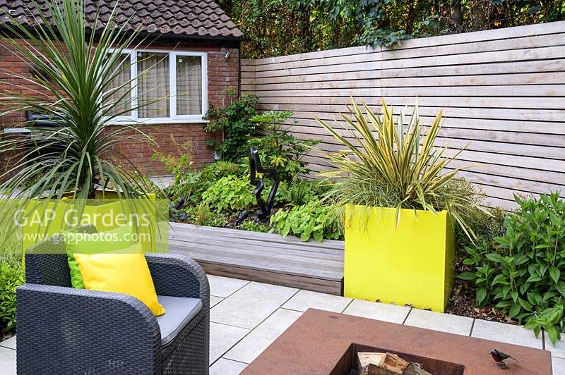 Small Modern Garden with sofa and armchairs around fire pit 