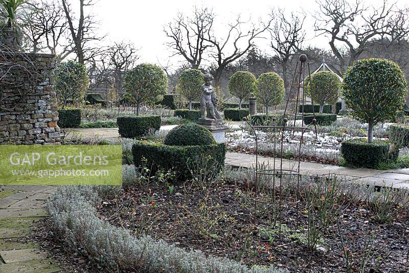 Parterre, view over bed with metal plants supports to lollipop topiary