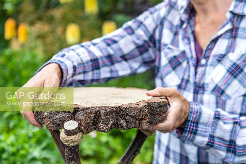 Woman adding a slice of wood to the top of tripod structure to make a table