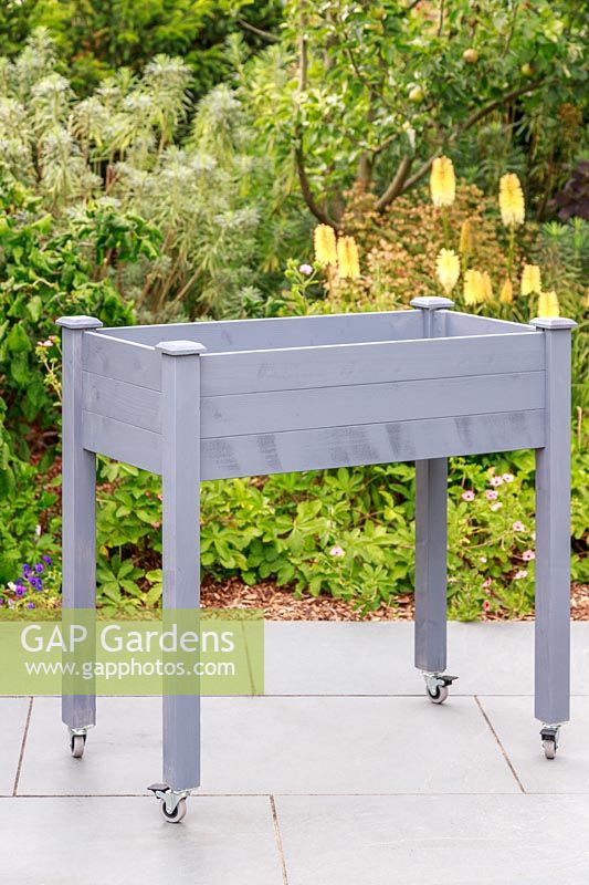 Newly-painted raised wooden planter on casters built from a kit