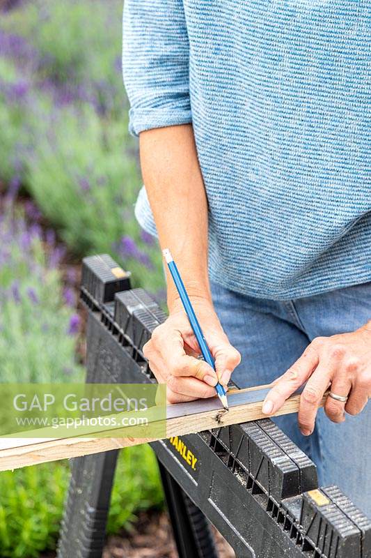 Woman using pencil to mark the correct length required to fill gaps in pallet. 