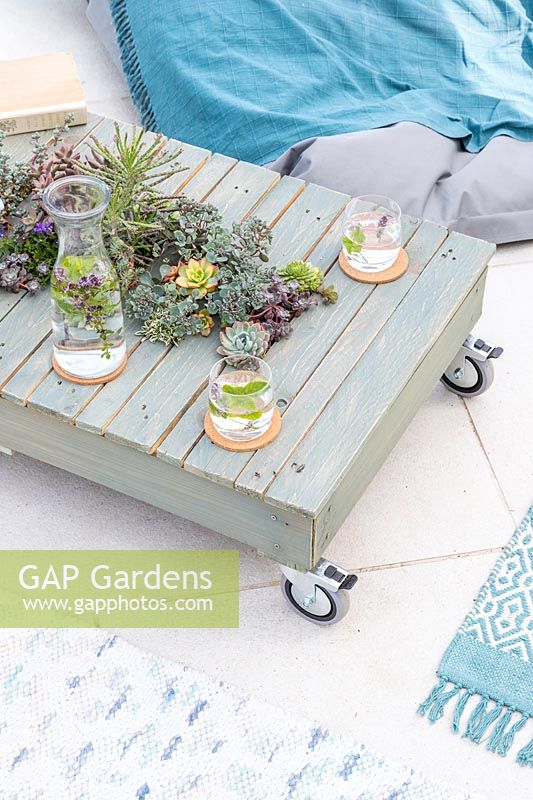 Finished pallet table with succulents on patio with rugs and beanbag seating. 