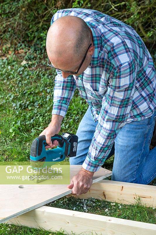 Man using jigsaw in order to create the handle for carrying the coldframe