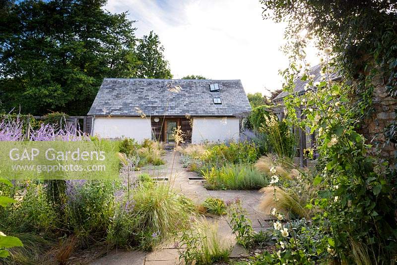 Courtyard garden with timber pergola, rill and planting including Stipa tenuissima, S. gigantea, Phlomis russeliana, Perovskia 'Blue Spire', irises and silvery stachys at Am Brook Meadow, Devon in August. 