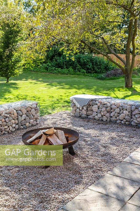 Finished firepit area with gabion benches filled with boulders and pebble surface