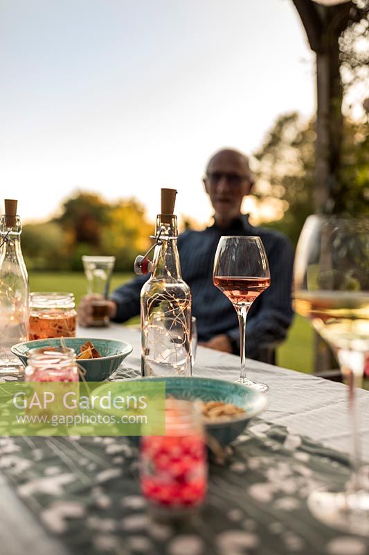 Glass bottles with light chains inside used as table decoration for evening garden party