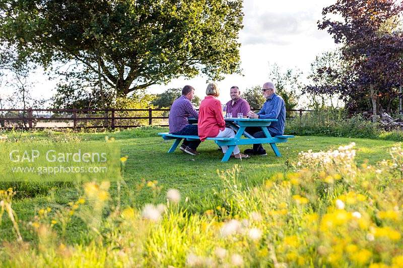 People sat at newly assembled picnic bench in meadow