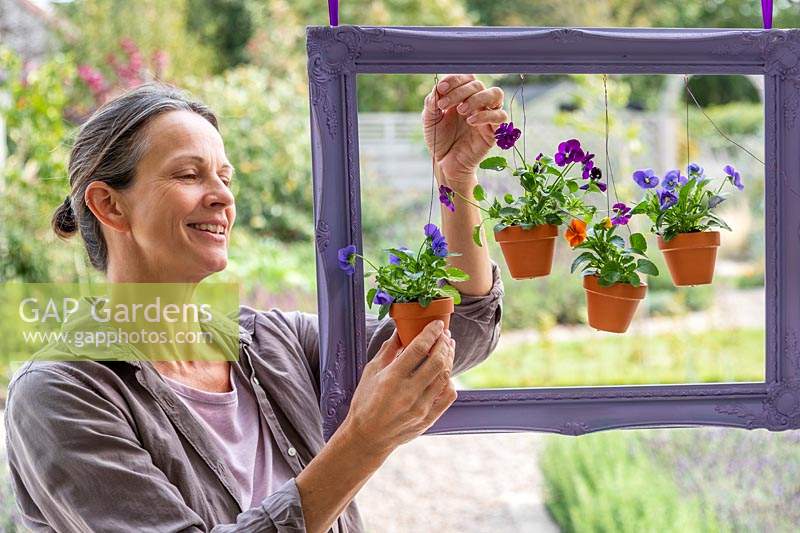 Woman adjusting the wires to arrange the hanging pots within the frame