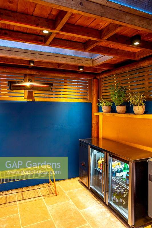 Garden room or pergola in small garden in West London at night with lighting. View towards fridges