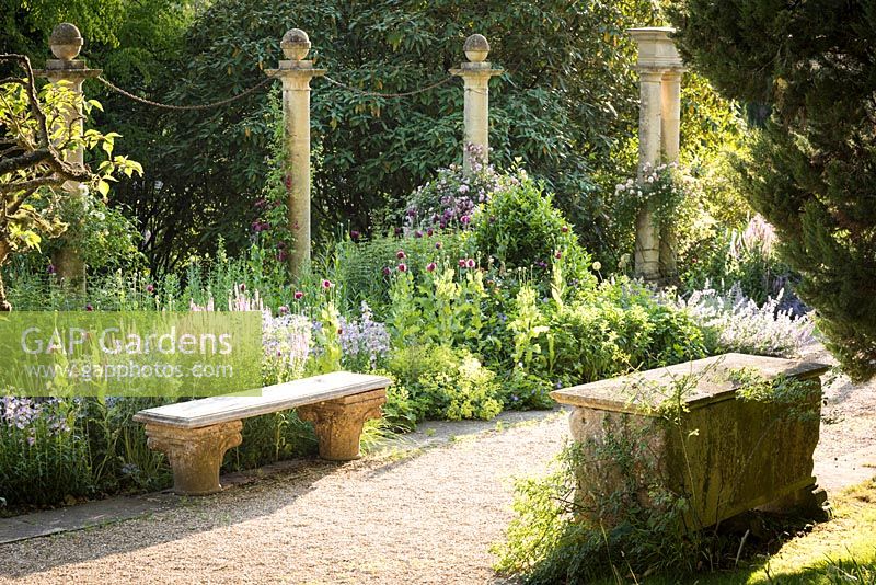 Stone benches either side of path, one on column capitals and another a Roman sarcophagus