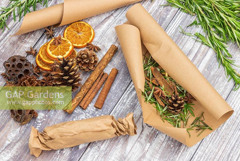 Scented fire starters made with Salvia rosmarinus syn. Rosmarinus - Rosemary - in brown paper with cinnamons sticks, orange slices, star anise and pine cones 