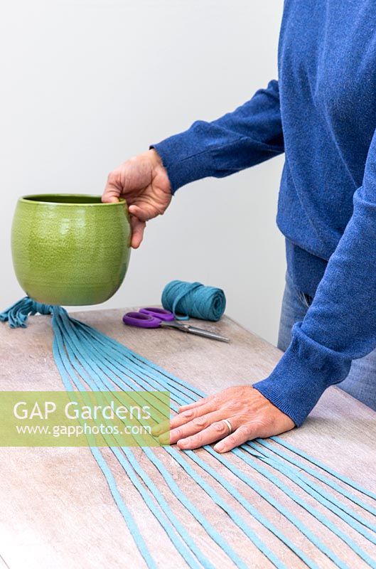 Woman using plant pot as a weight to hold fabric cord in place