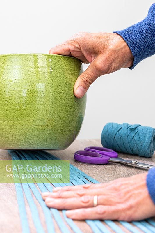 Woman using plant pot as a weight to hold fabric cord in place