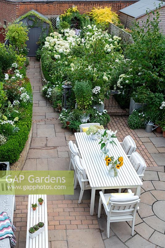 Bird's eye view of a small town garden, with dining and seating areas and white-themed borders. 