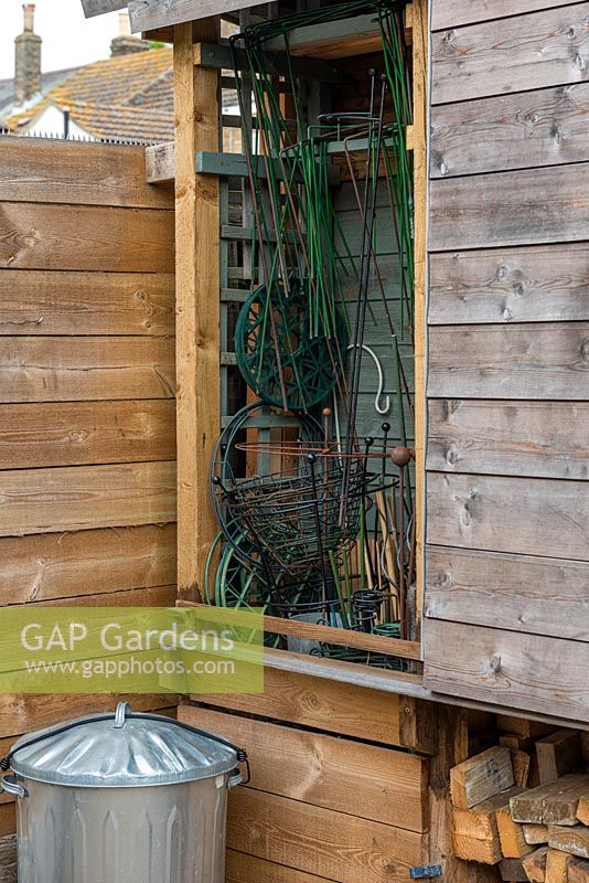 Attached to the back of a garden shed is a sliding door concealing plant supports.