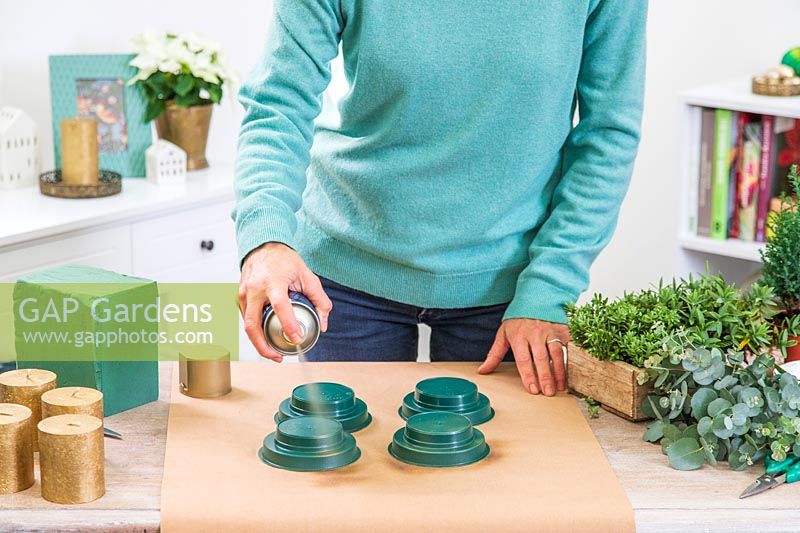 Woman spraying plastic candle holders gold