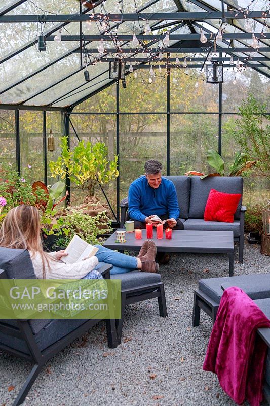 Father and daughter relaxing on lounge furniture in a greenhouse, view of rood with suspended lighting